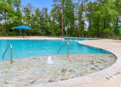 Thumbnail 23 of 24 - a swimming pool with a fountain in the middle of it and trees in the background