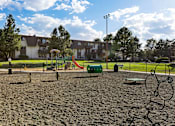 Thumbnail 32 of 42 - A playground with a sandy area and a swing set.