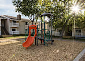 Thumbnail 29 of 42 - A playground with a red slide and a green swing set.