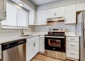 Thumbnail 1 of 42 - Aurora, CO Apartments – Ivy Crossing – A modern kitchen with white cabinets and stainless steel appliances.