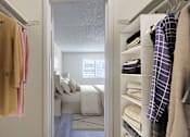 Thumbnail 12 of 42 - A bedroom with a bed and a closet with clothes.