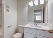 Thumbnail 22 of 42 - Aurora, CO Apartments – Ivy Crossing – A white bathroom with a toilet, sink, and shower.