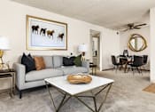 Thumbnail 17 of 42 - A living room with a grey couch, a coffee table, and a painting of horses.
