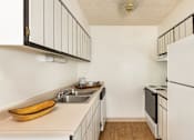 Thumbnail 16 of 42 - Aurora, CO Apartments – Ivy Crossing – A kitchen with a white refrigerator and a wooden bowl on the counter.