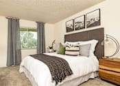 Thumbnail 20 of 42 - A bedroom with a large bed, a nightstand, and a window with curtains.