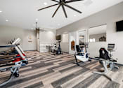Thumbnail 4 of 42 - Aurora, CO Apartments – Ivy Crossing – A gym with treadmills, exercise bikes, and a ceiling fan.