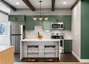 Thumbnail 33 of 42 - A kitchen with green cabinets and a white island.