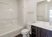 Thumbnail 15 of 26 - A white bathroom with a toilet, sink, and bathtub.