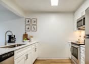 Thumbnail 2 of 35 - Everett, Washington, Apartments - Woodbrook - Kitchen With Stainless Steel Appliances, Vinyl Plank Flooring, Quartz Countertops, White Cabinets, And A Breakfast Bar.