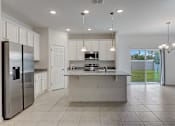 Thumbnail 12 of 36 - A modern kitchen with a refrigerator, sink, and cabinets.