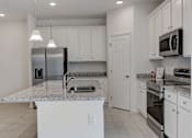Thumbnail 14 of 36 - A kitchen with white cabinets and appliances.