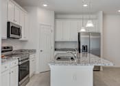 Thumbnail 13 of 36 - A kitchen with white cabinets and a marble countertop.