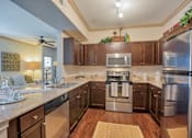 Thumbnail 12 of 33 - kitchen with stainless steel appliances and wood floor and wood cabinets and marble counter