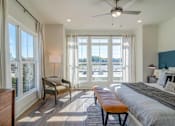Thumbnail 5 of 13 - Pet-Friendly Homes In Edgewood, GA – LaFrance Square- A bedroom with a large bed, a chair, and a window with a view of the city.