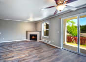 Thumbnail 6 of 30 - Apartments for Rent in Issaquah, WA - Langara - Living Room with Wood-Style Flooring, Window, Ceiling Fan, Fireplace, and Sliding Glass Door with Access to Patio