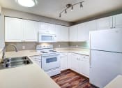 Thumbnail 5 of 30 - Two-bedroom apartments in Issaquah, WA - Langara - Fully Equipped Kitchen with White Appliances, White Cabinets, and Dual Sink