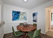 Thumbnail 16 of 17 - A dining room with a round wooden table and four green chairs.