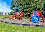 Thumbnail 9 of 17 - A playground with a red slide and a blue and red climbing structure.
