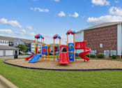 Thumbnail 11 of 25 - playground at Lancaster Place Apartments in Calera, AL with colorful play equipment and outdoor recreation for families.