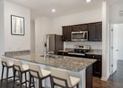 Thumbnail 32 of 63 - A kitchen with a granite countertop and bar stools.