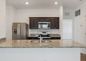 Thumbnail 31 of 63 - A kitchen with granite countertops and stainless steel appliances.