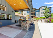 Thumbnail 16 of 18 - A patio area with a stone wall and a wooden roof.