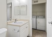 Thumbnail 22 of 30 - a bathroom with a sink and a mirror and a laundry room