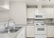 Thumbnail 17 of 30 - an empty kitchen with white appliances and granite counter tops