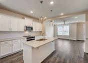 Thumbnail 2 of 16 - Townhomes for Rent in Gallatin, TN - The Gardens at Preston Park - Kitchen with Wood-Style Flooring, Stainless Steel Appliances, White Cabinetry, Qaurtz Countertops, and Cooking Island with Hanging Overhead Lights