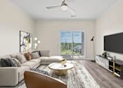 Thumbnail 4 of 21 - Spacious living room with couch, coffee table, and TV at Hawks Landing Apartments in Hickory, NC