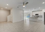 Thumbnail 16 of 36 - A spacious, empty room with a ceiling fan and tiled flooring.