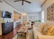 Thumbnail 16 of 33 - Living room with wood floors and couches and chairs and windows with blinds and ceiling light/fan