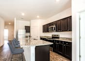 Thumbnail 28 of 63 - A kitchen with black cabinets and a granite countertop.