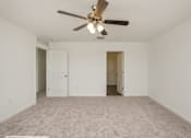 Thumbnail 44 of 75 - A room with a ceiling fan and carpeted floor.