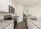 Thumbnail 39 of 75 - A kitchen with granite countertops and white cabinets.