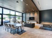 Thumbnail 14 of 19 - Miami, FL, Apartments - MB Station - Spacious Clubouse with Concrete Flooring, Black Lounge Couches, Table with Chairs, Ping Pong Table, Large TV, Balck Walls, Wood-Style Wall Details, and Window Wall.