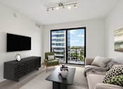 Thumbnail 6 of 30 - Bright open-concept living room at MB Station with oversized windows, contemporary finishes, and city views in Miami's Coral Way neighborhood near Brickell.