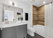 Thumbnail 10 of 30 - Modern bathroom with quartz vanity, wood-accent shower surround, and contemporary fixtures at MB Station apartments in Coral Way, Miami.