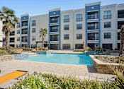 Thumbnail 1 of 22 - Apartments for Rent in North Little Rock, AR 72114– Metropolitan-   A pool surrounded by a patio and a building.