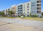 Thumbnail 22 of 22 - 1, 2 -Bedroom Apartments for Rent in North Little Rock, AR – Metropolitan– A row of modern apartment buildings are lined up on a street.