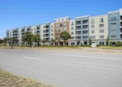Thumbnail 21 of 22 - Pet-Friendly Rentals in North Little Rock, AR – Metropolitan – A row of apartment buildings with trees in front.