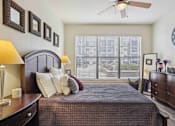 Thumbnail 9 of 22 - Apartments for Rent in North Little Rock, AR 72114– Metropolitan-   A bedroom with a bed, nightstand, and a clock on the wall.