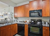Thumbnail 2 of 22 - 1, 2 -Bedroom Apartments for Rent in North Little Rock, AR – Metropolitan– A kitchen with wooden cabinets and a black microwave.