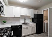 Thumbnail 13 of 24 - Kitchen with black appliances and open layout in renovated Atlanta rental apartment.