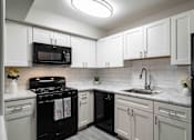 Thumbnail 12 of 24 - Kitchen with gas stove and white cabinets in updated apartment at Mirador at Peachtree.