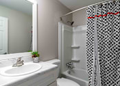 Thumbnail 19 of 24 - Bathroom with updated vanity and patterned shower curtain in renovated Atlanta apartment.