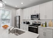 Thumbnail 1 of 24 - Modern kitchen with stainless steel appliances and white cabinets inside Mirador at Peachtree apartments in Atlanta, GA.