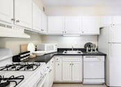 Thumbnail 14 of 66 - A white kitchen with black countertops and appliances.