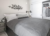 Thumbnail 24 of 36 - One-Bedroom Modern Apartments in Seattle, WA - Origin - Bedroom with Bed, Nightstand with Lamp, Wall Art, Spacious Closet, and Grey Carpet