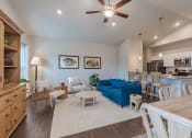 Thumbnail 5 of 22 - a living room with a blue couch and a kitchen with a table and chairs